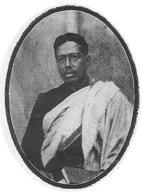 Half-length photographic portrait of Bipin Chandra Pal in spectacles, wearing a dark coat with a light shawl over one shoulder, printed within an oval frame.